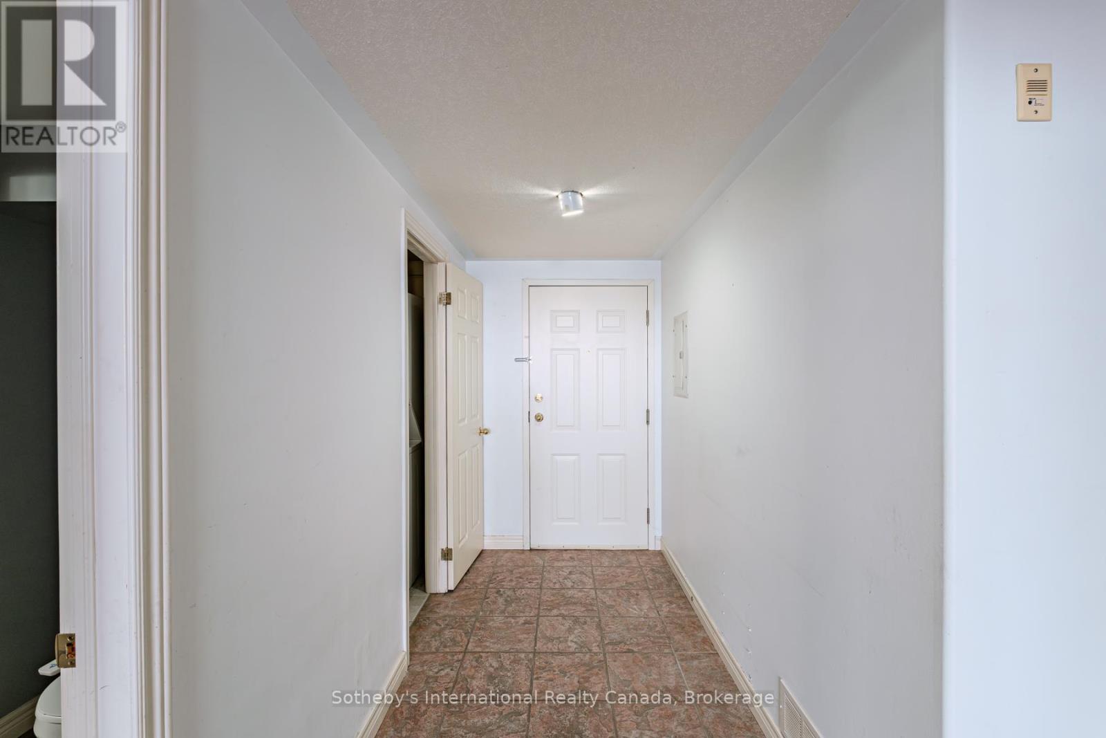Entry hallway with a tiled floor, white front door, and open doorway.