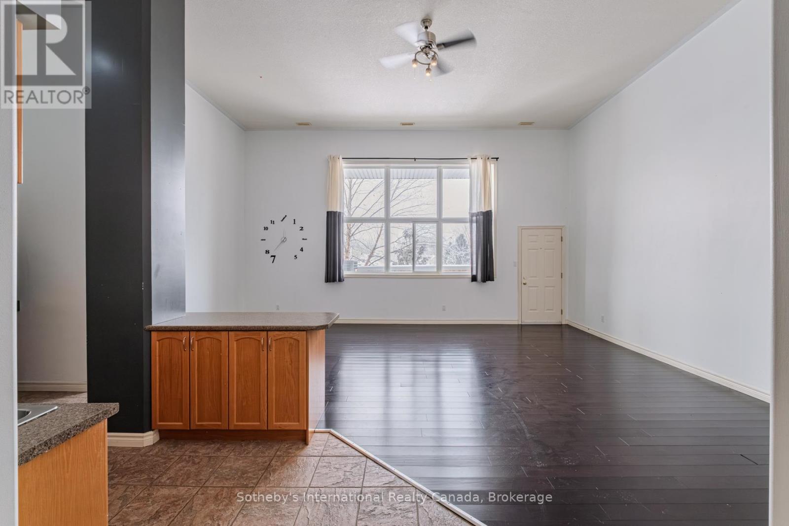 Open living area with dark flooring, wood kitchen island, and a large curtained window.