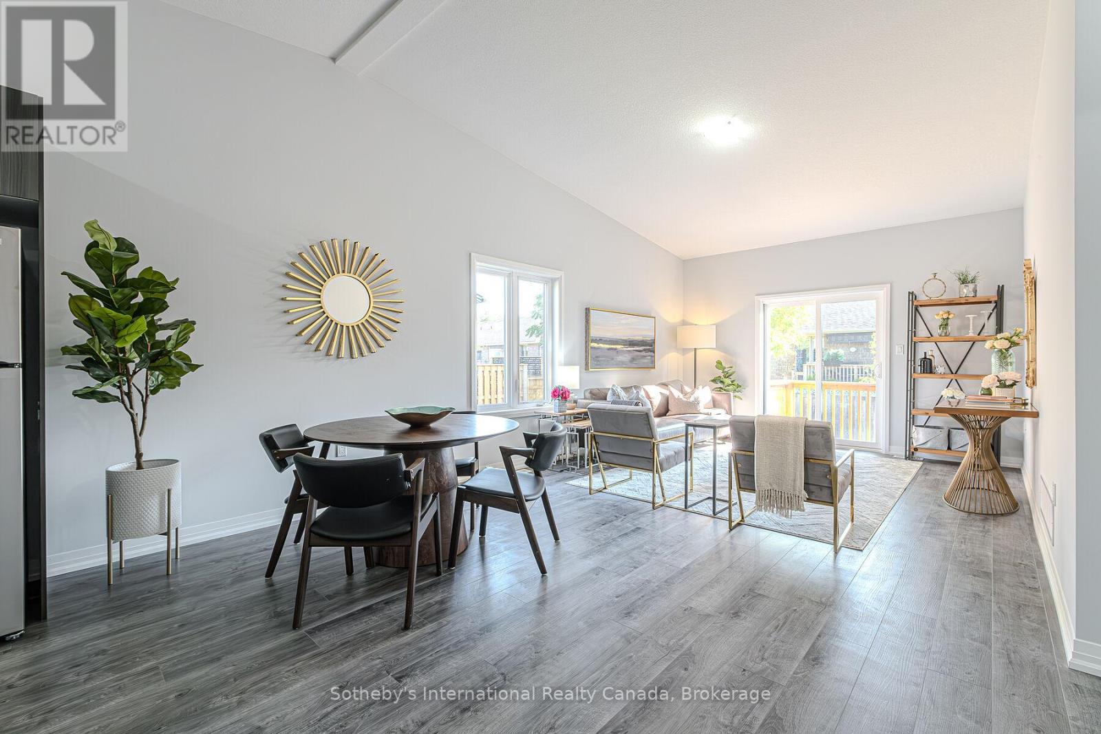 Open-plan dining and living room with a vaulted ceiling, furnished seating, and sliding doors to a deck.