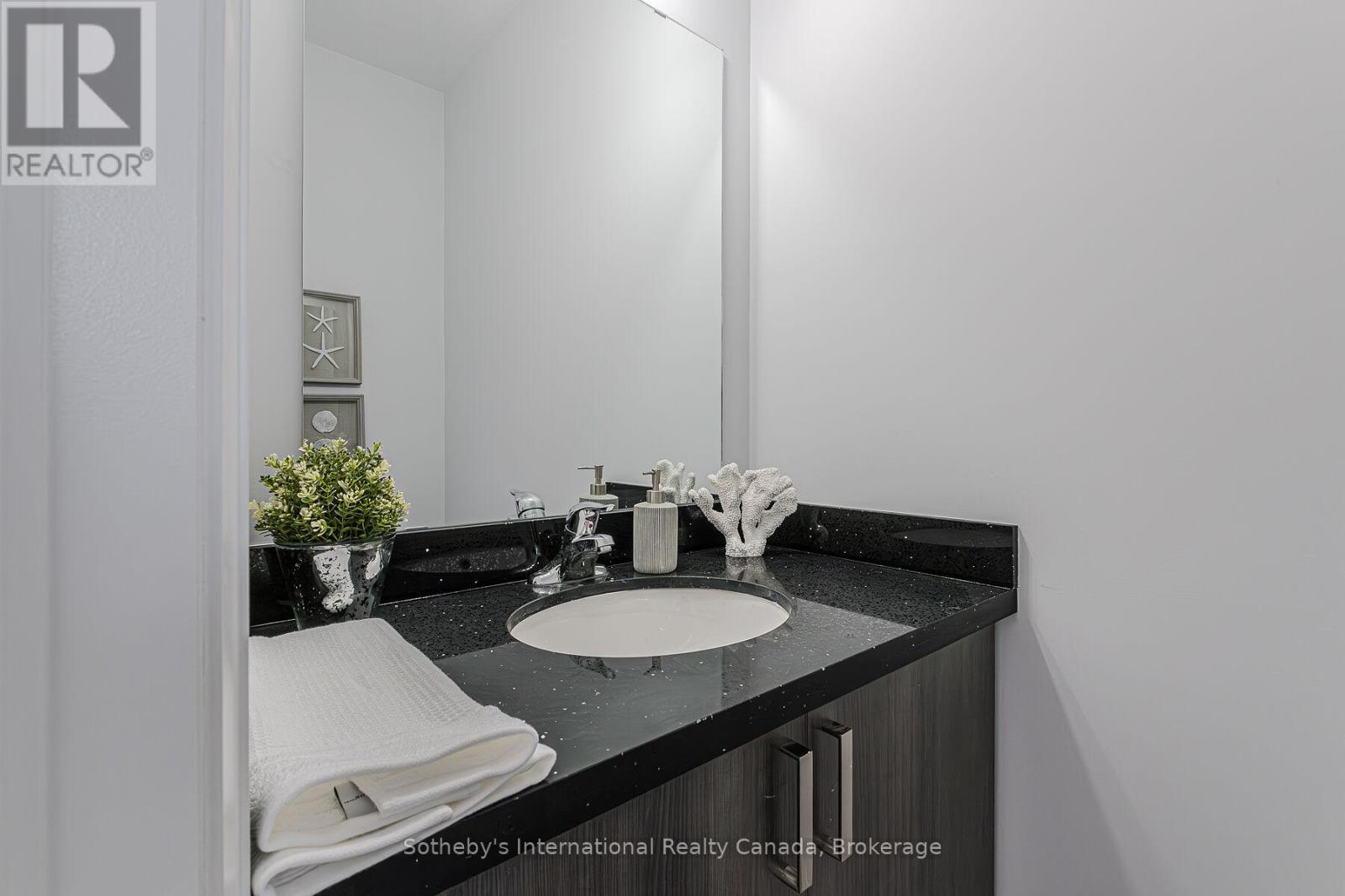 Bathroom vanity with a black countertop, oval sink, large mirror, and folded white towels.