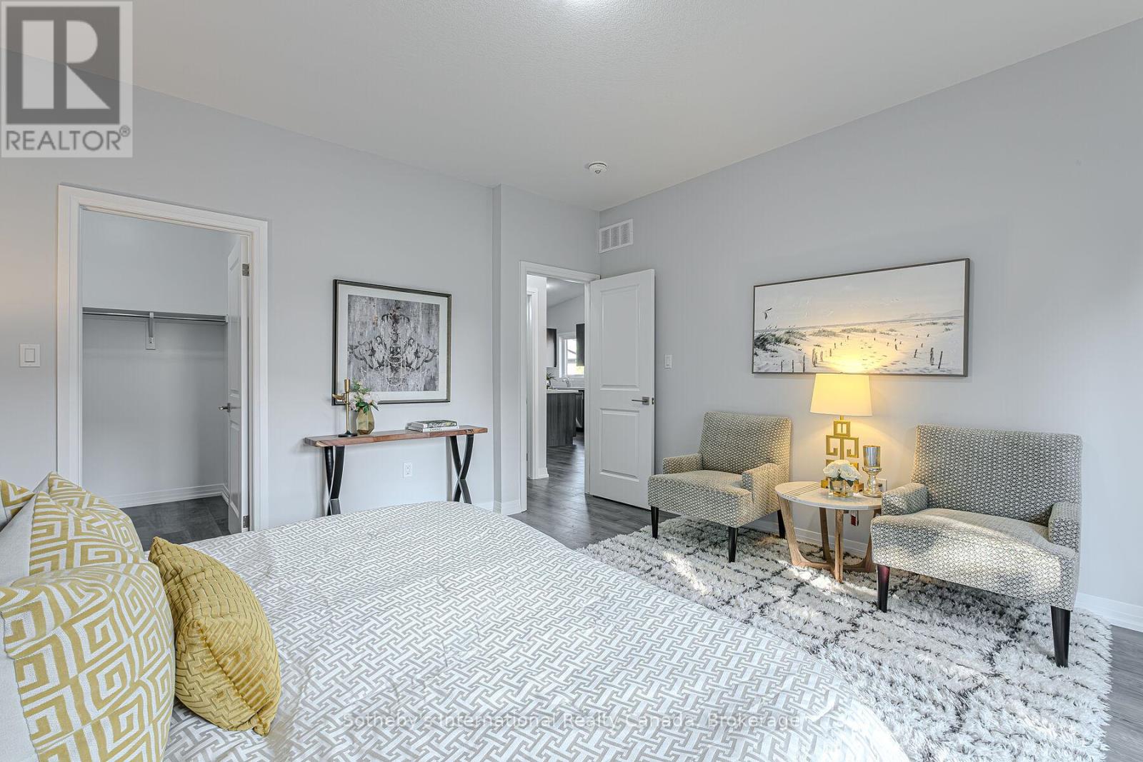 Staged bedroom with a patterned bed, two upholstered chairs, and an open closet.