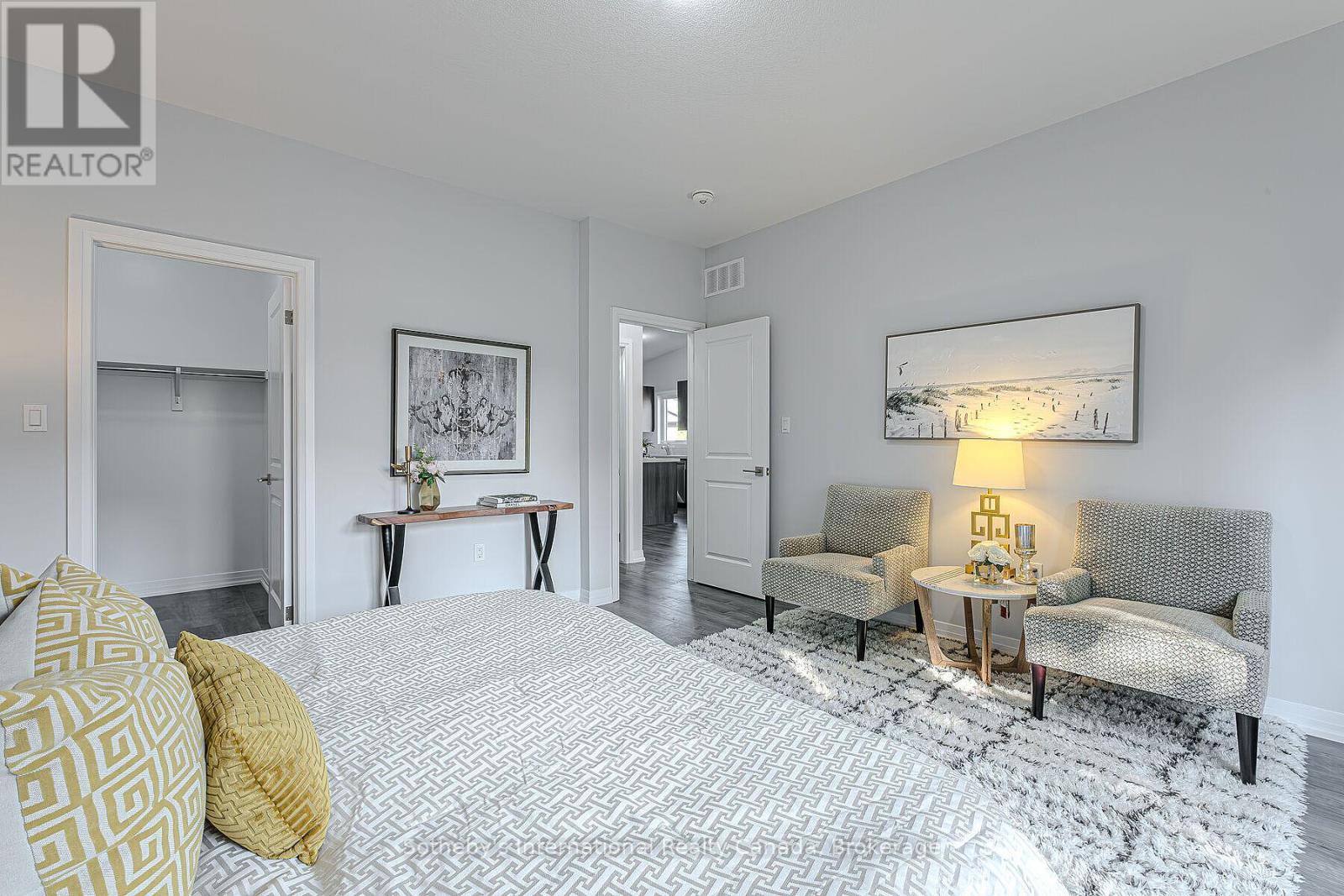 Staged bedroom with patterned bed, two armchairs, and an open closet.