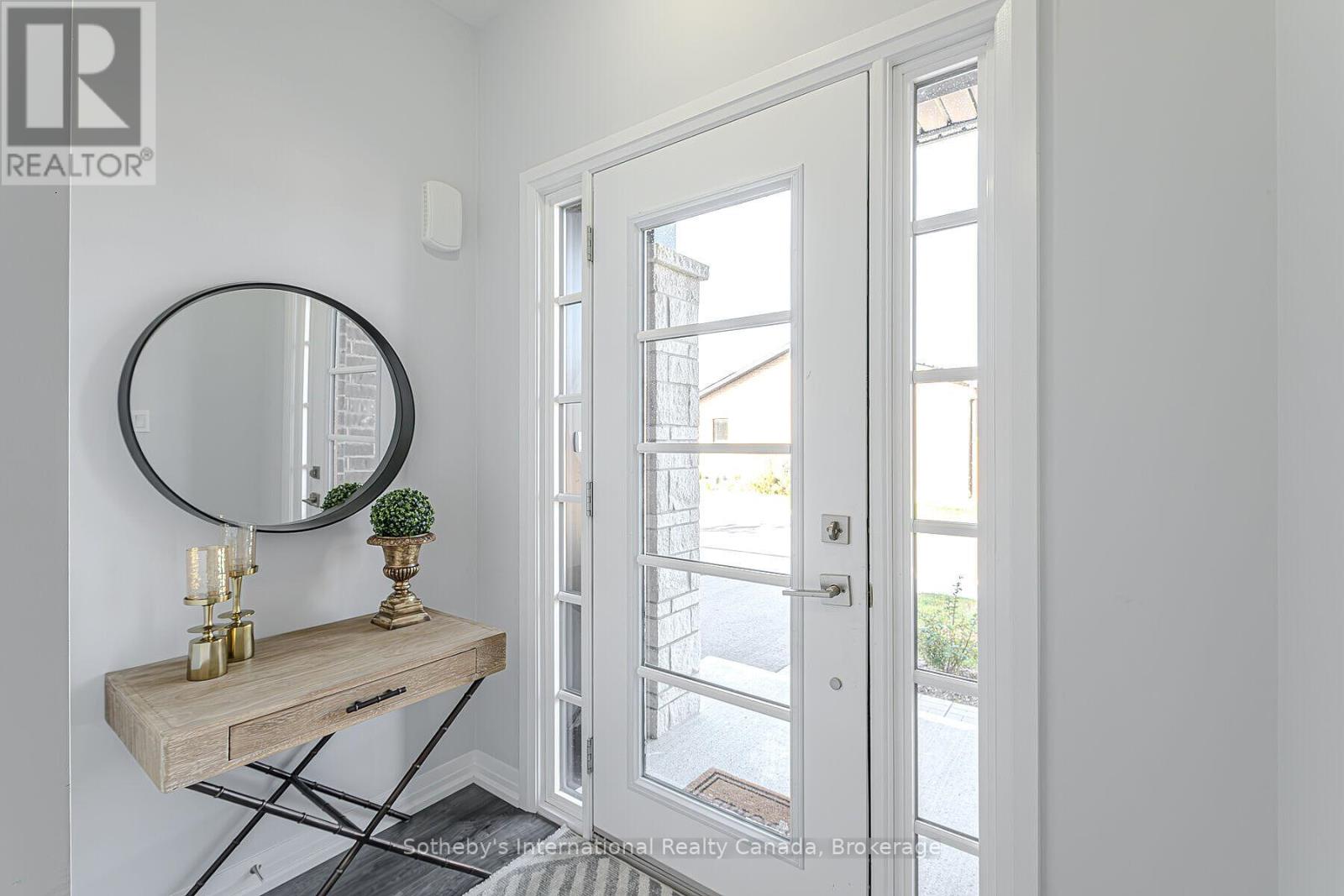 Entry foyer with a glass-paneled front door, round mirror, and slim console table.