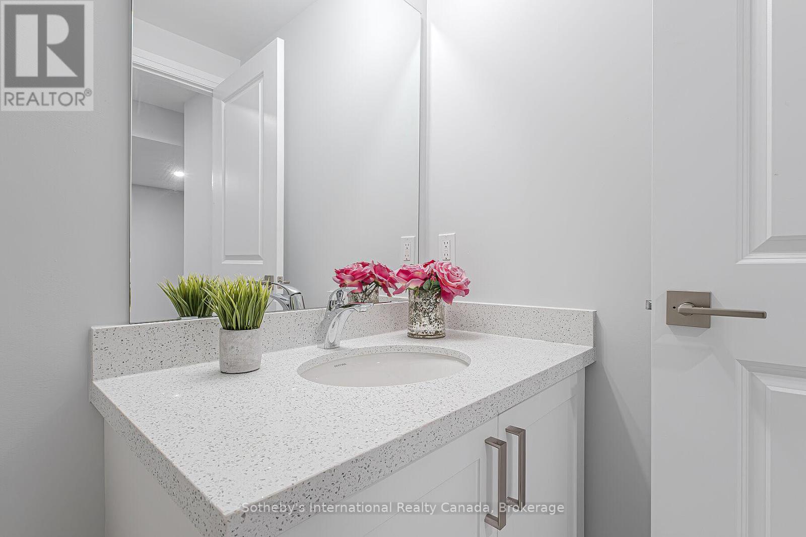 Bathroom vanity with a speckled countertop, oval sink, large mirror, and pink flowers.