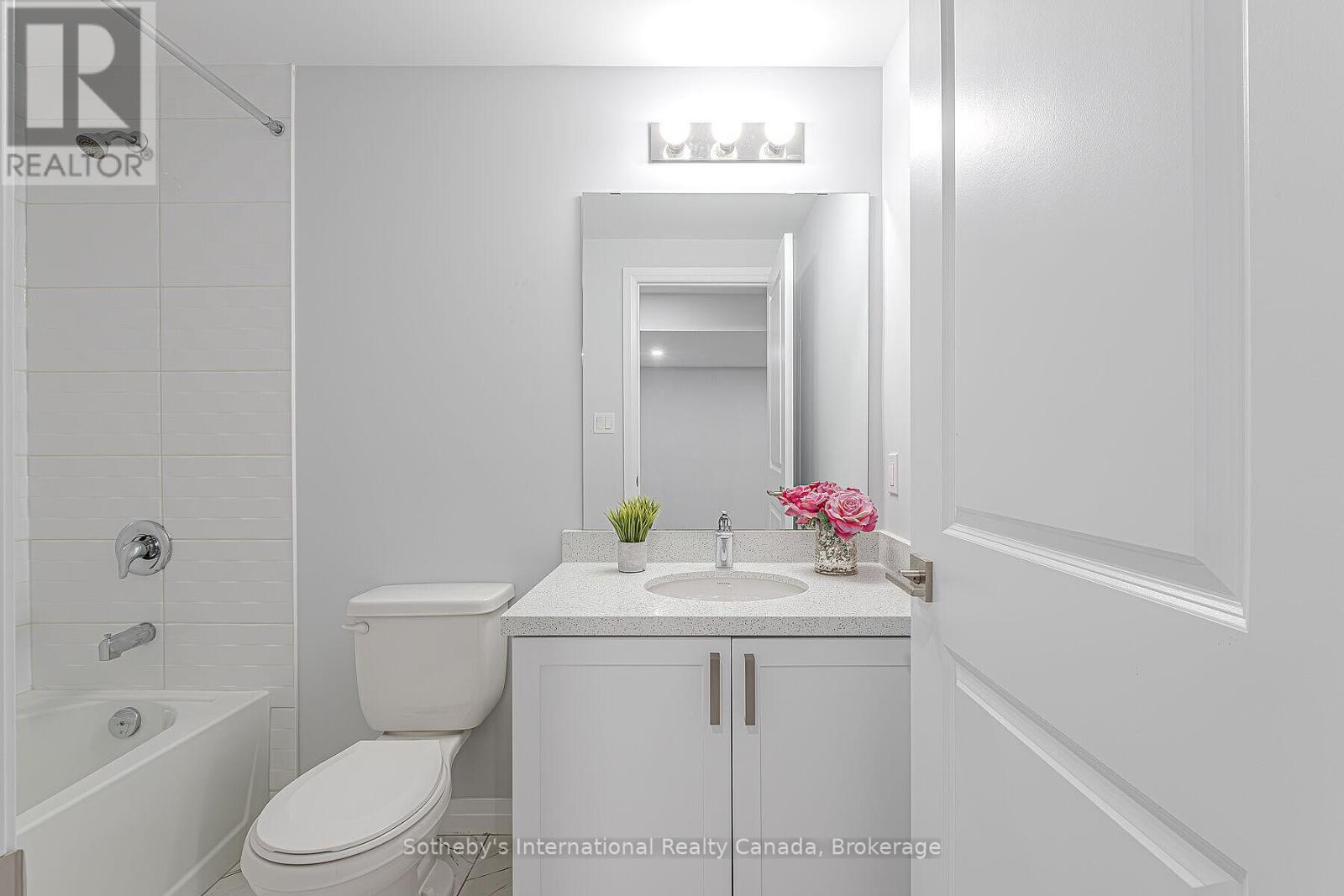 Bathroom with a bathtub and tiled shower beside a vanity with a speckled countertop.