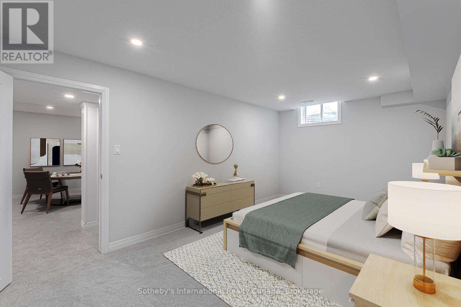 Staged bedroom with a low window, bedside furnishings, and an open doorway to a study.