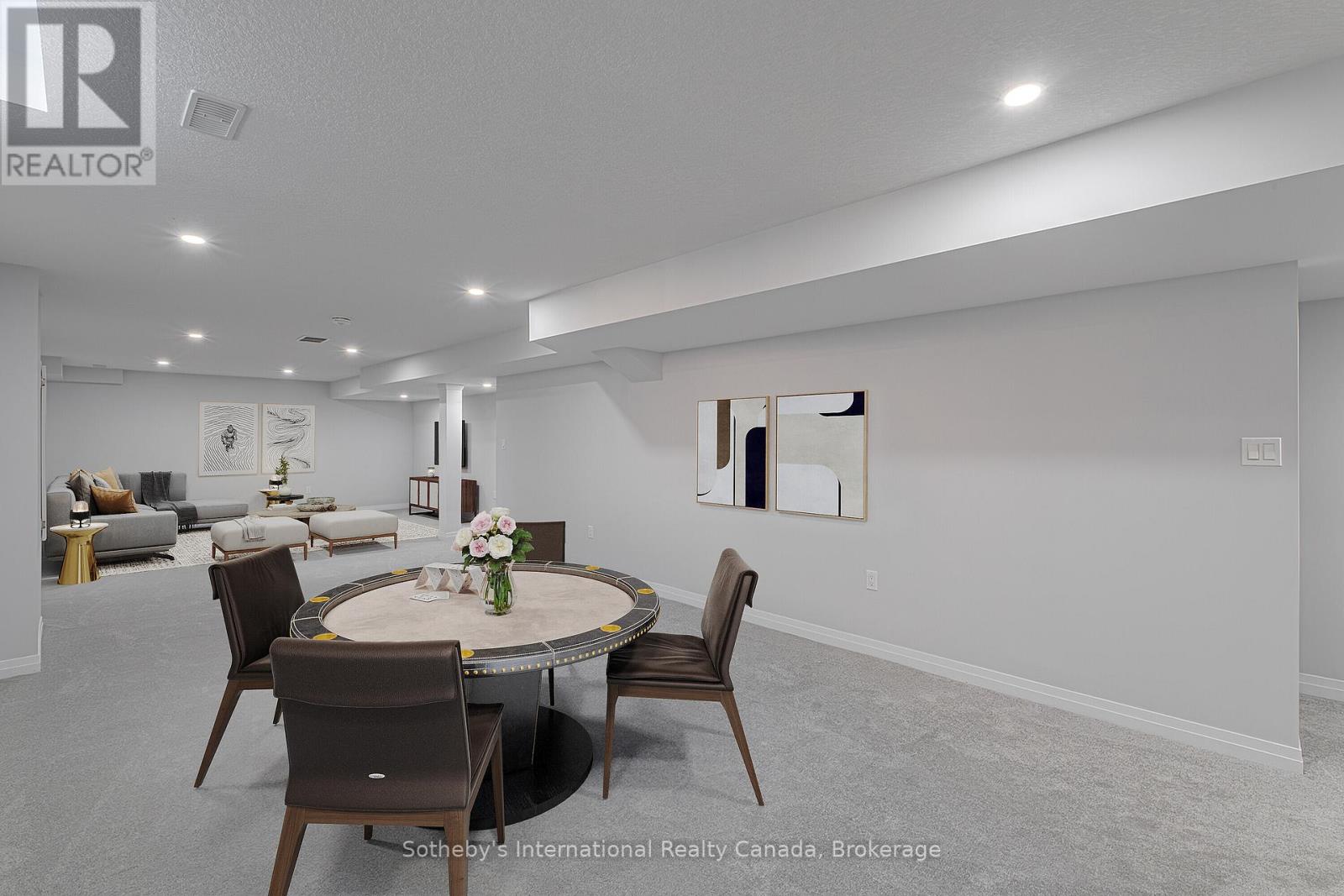 Staged recreation room with a round dining table, gray carpet, and a lounge seating area.
