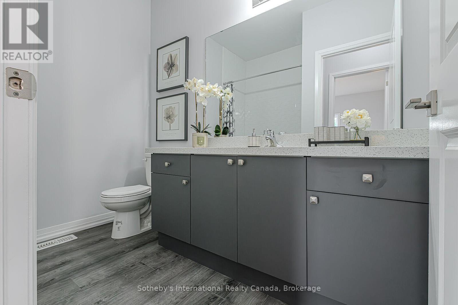 Bathroom with a dark gray vanity, wide mirror, and white orchid arrangements.
