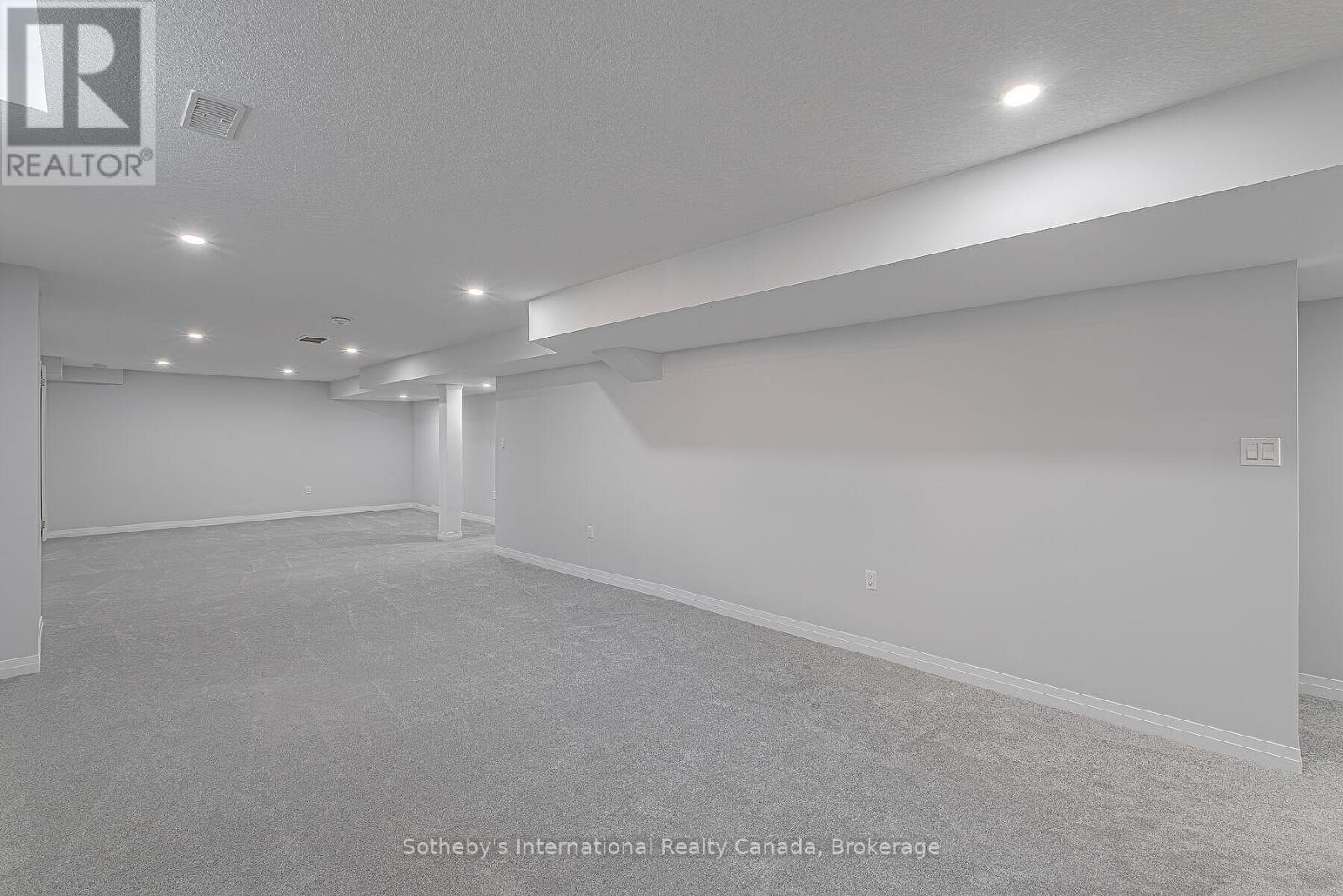 Empty carpeted basement with recessed lighting and a supporting column.