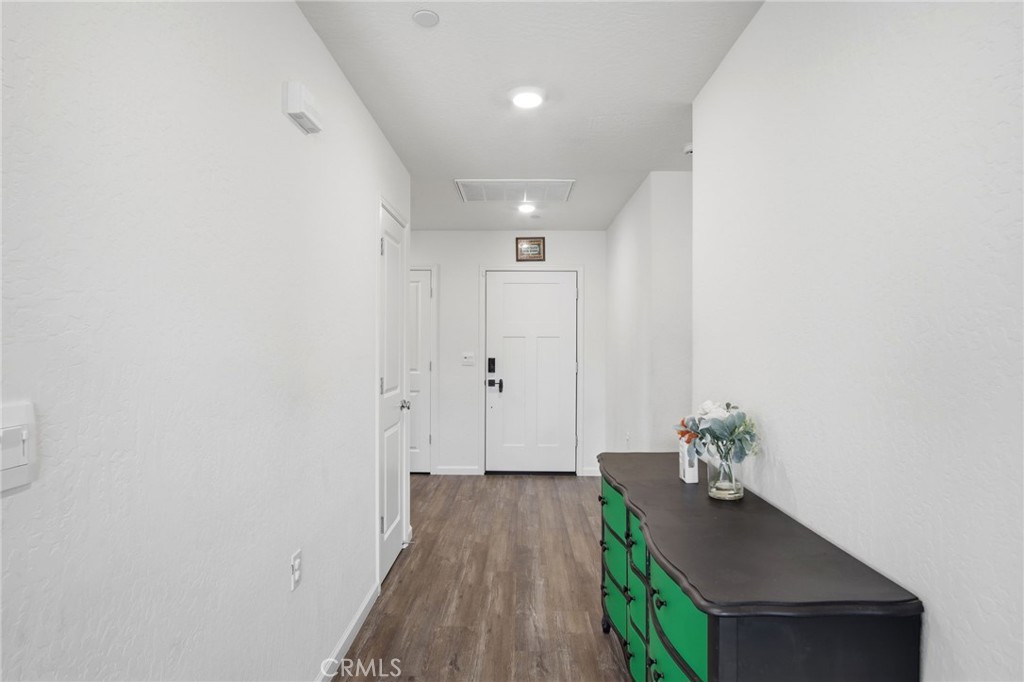 Entry hall with a white front door, wood-look flooring, and a green console cabinet.