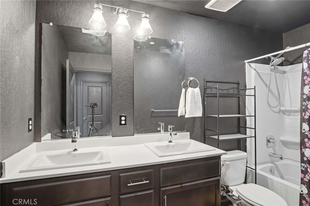 Bathroom with a dark double vanity, large mirrors, and a bathtub-shower.