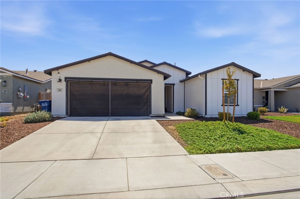 Single-story white home with dark trim, a double garage, broad driveway, and small front lawn.