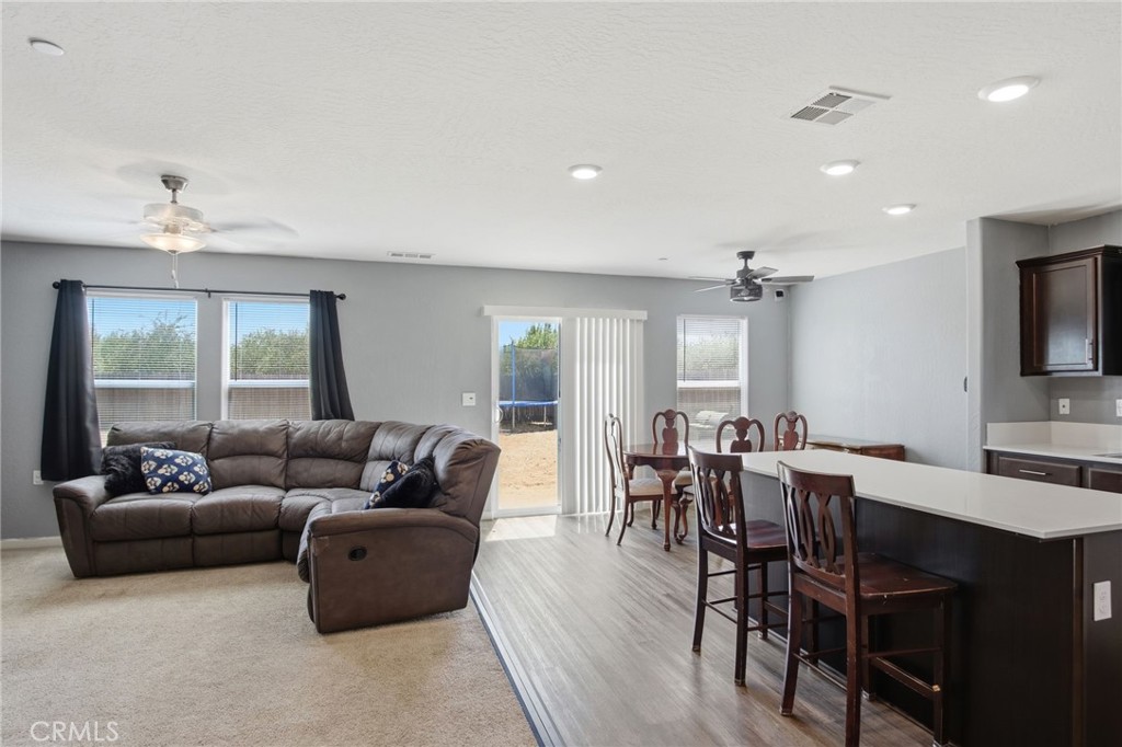 Open-plan living and dining area with a brown sectional, dining table, and kitchen island with bar stools.