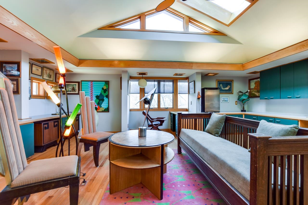 Living room with vaulted ceiling, clerestory windows, teal cabinets, and a colorful rug.