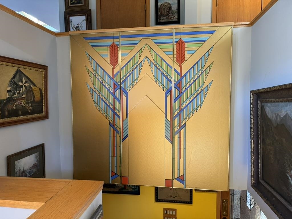 Geometric gold-and-blue decorative panel overlooking a stairwell, surrounded by framed artwork.