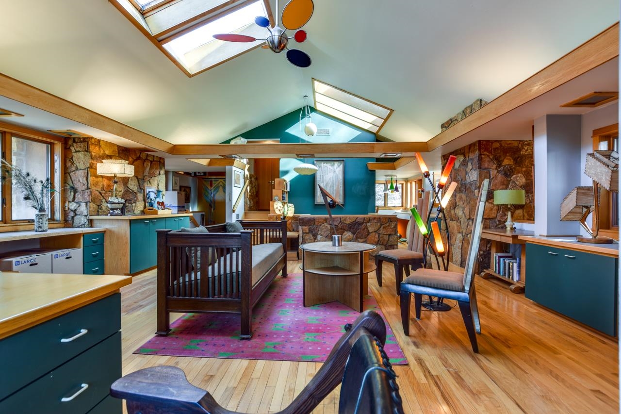 Open-plan living room with skylights, exposed beams, stone walls, and teal cabinetry.
