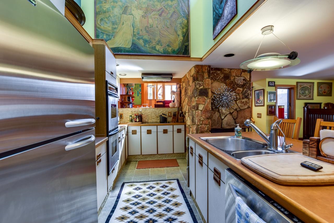Kitchen with stainless appliances, a double sink, and a prominent stone masonry feature.