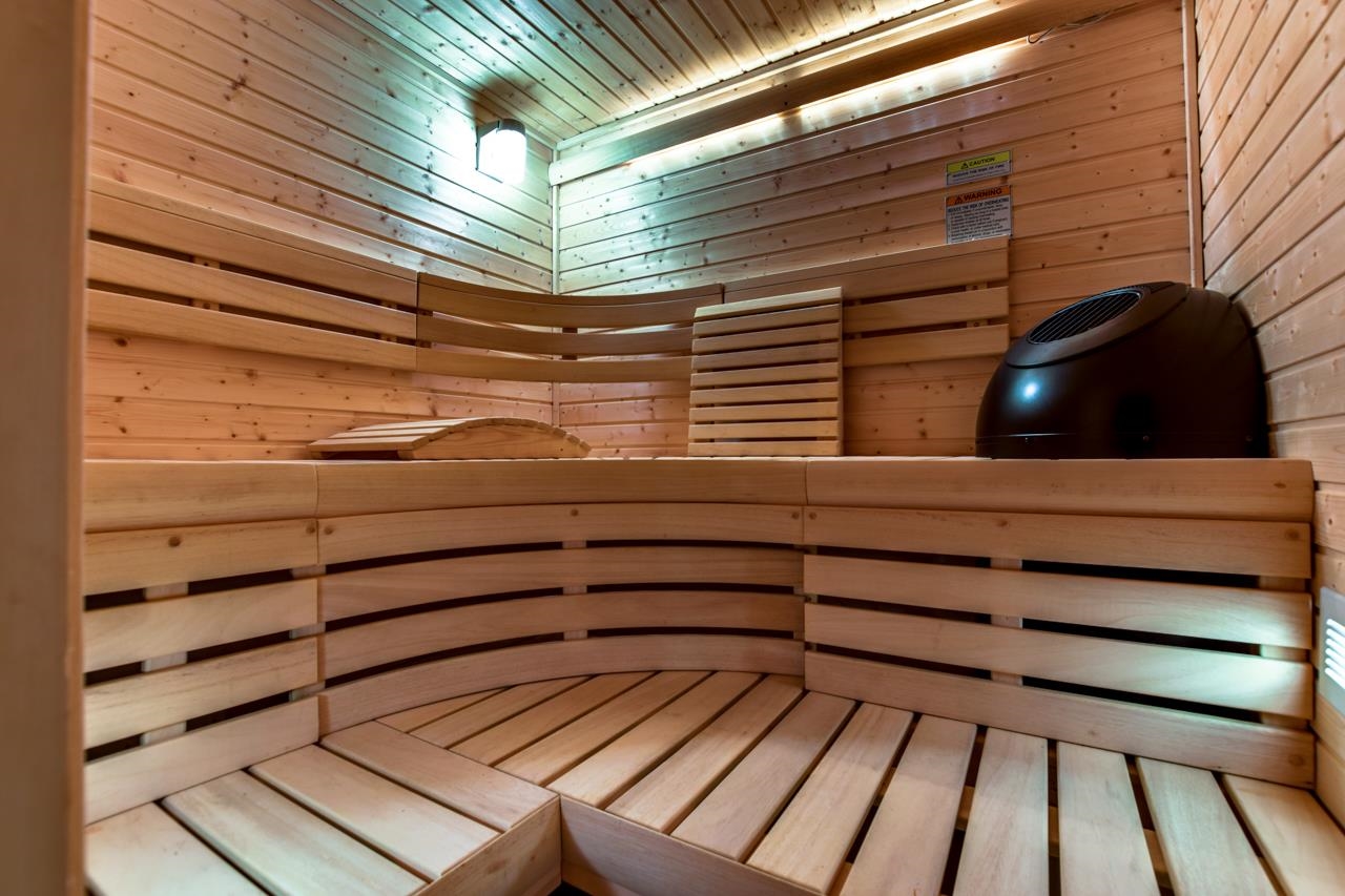 Wood-lined sauna with tiered benches and a black heater.