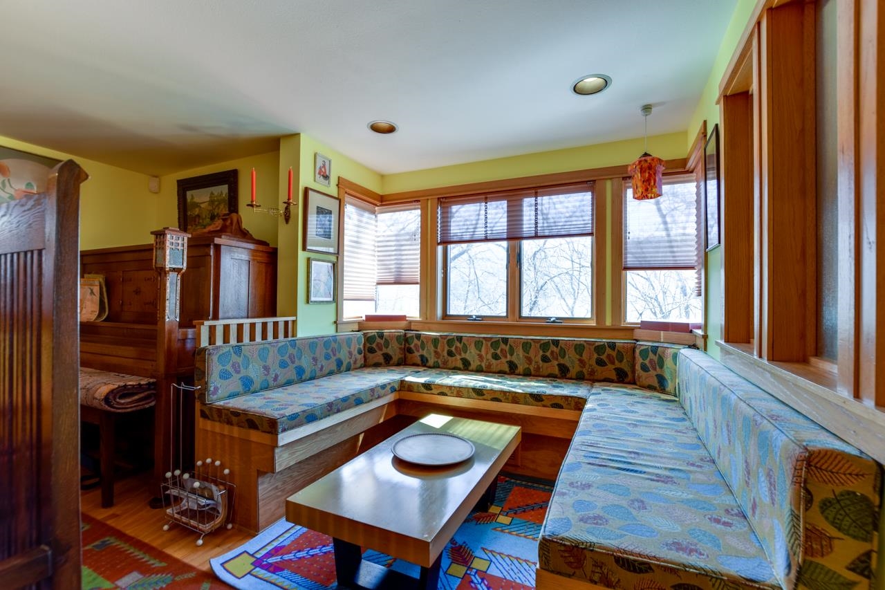 Sitting nook with a wraparound upholstered bench, coffee table, and large bay windows.