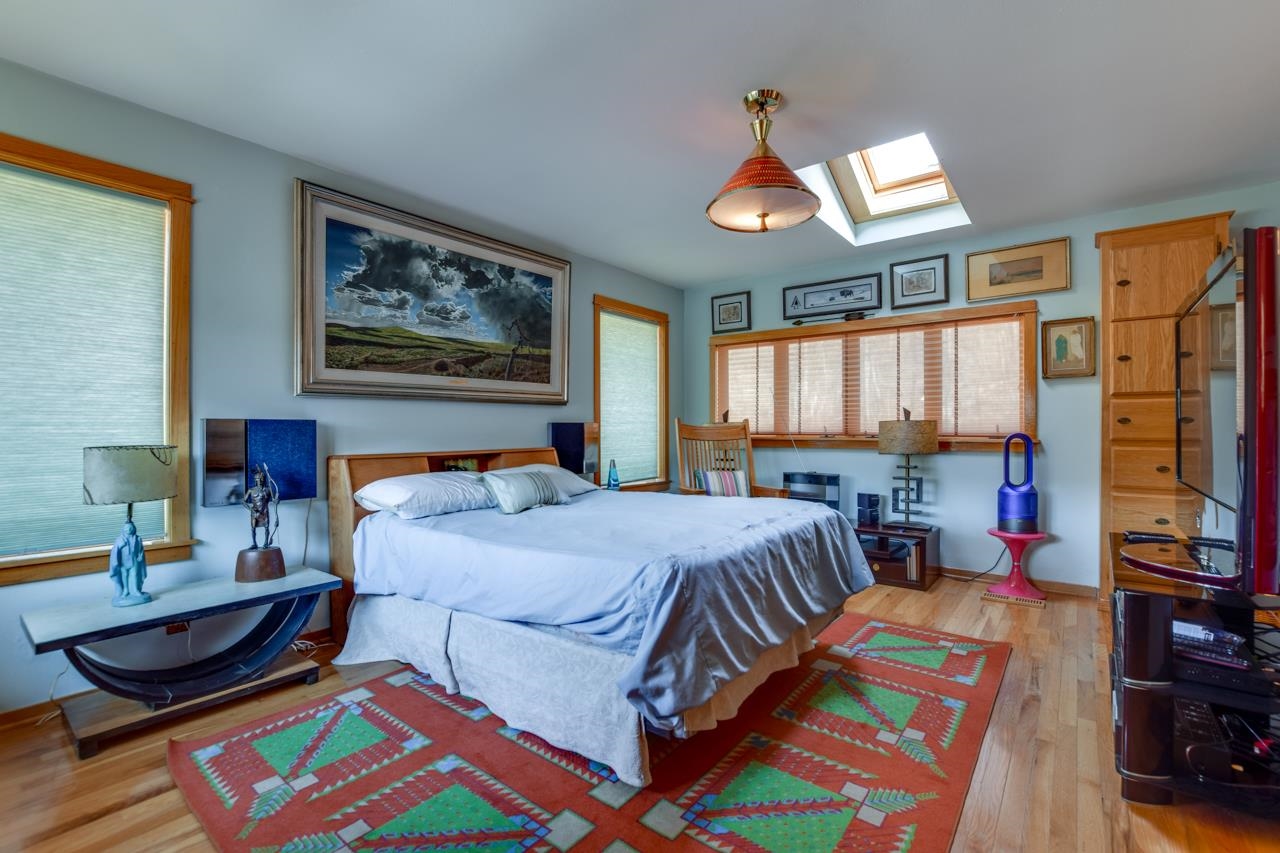 Furnished bedroom with a large bed, colorful patterned rugs, and a skylight.