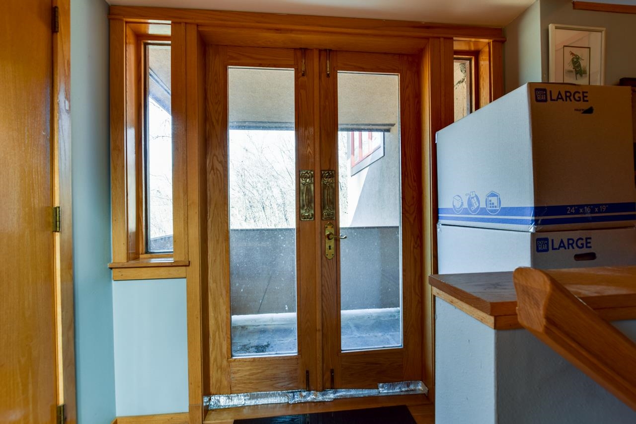 Entryway with wood-framed glass double doors, sidelights, and stacked moving boxes.