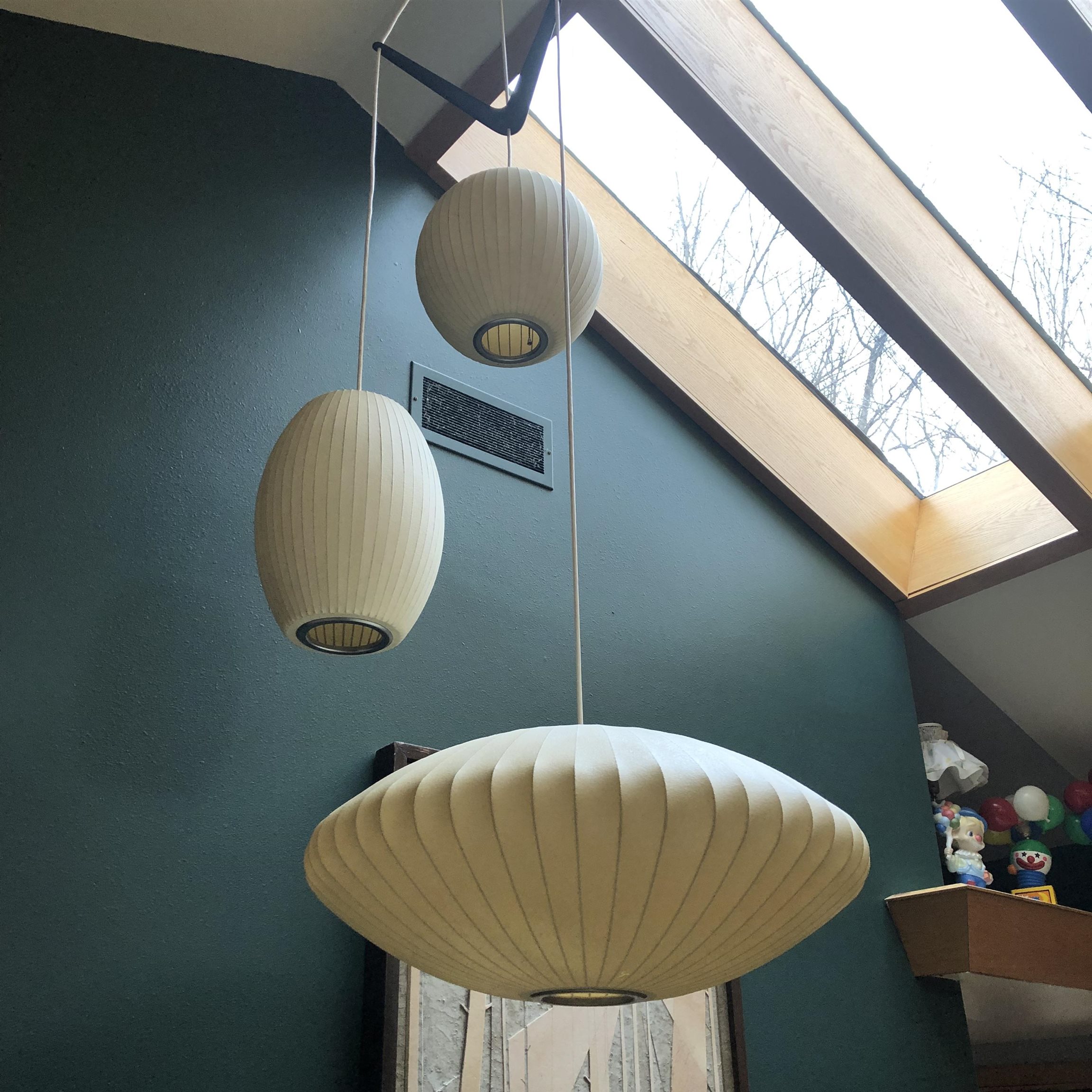 Three cream pendant lights hang beneath a large wood-framed skylight.