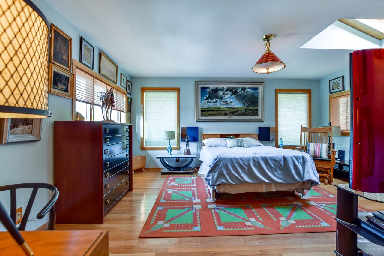 Bedroom with a large bed, geometric rug, framed artwork, and bright red cabinet.