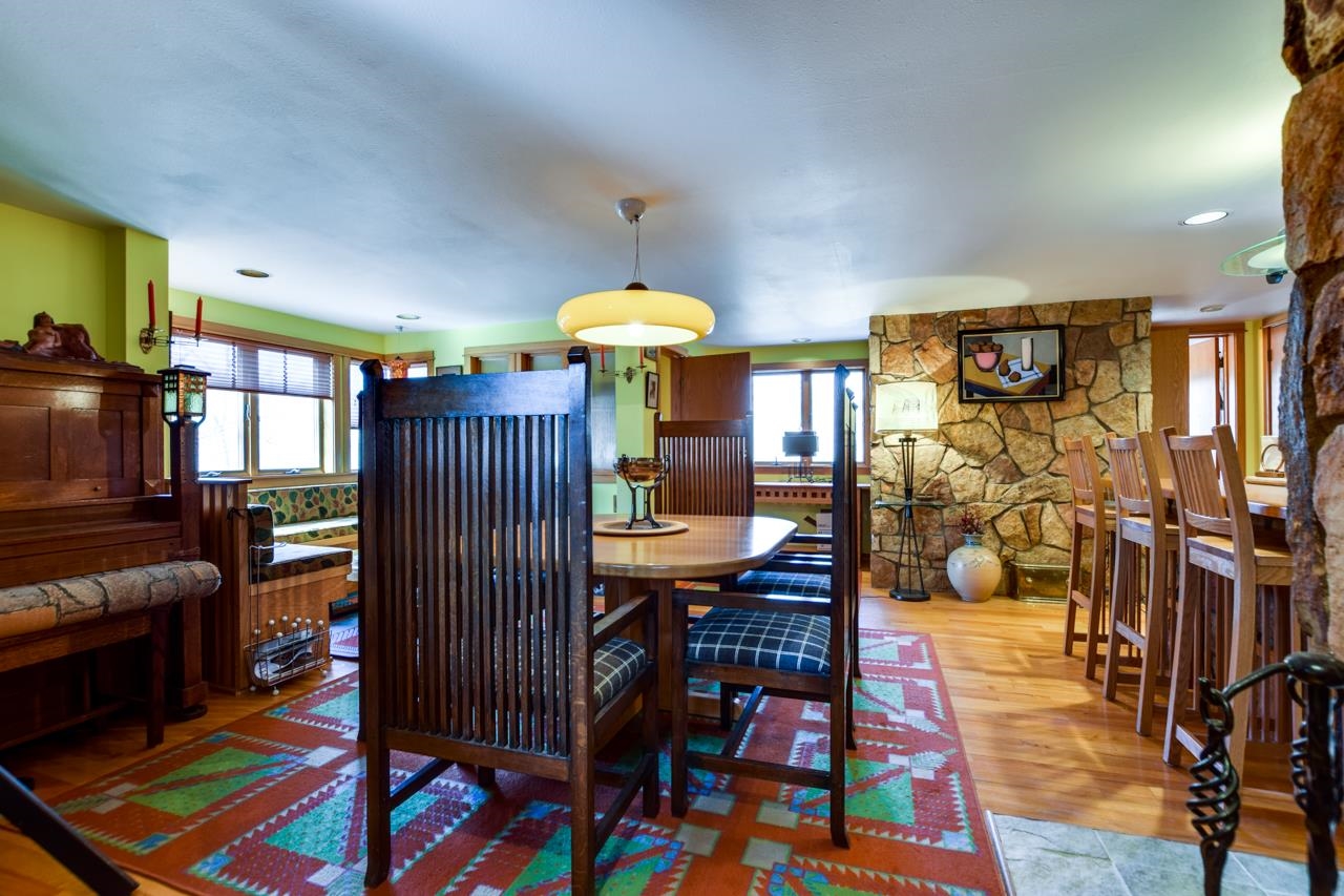 Dining room with a dark wood table, colorful rugs, and a stone fireplace.