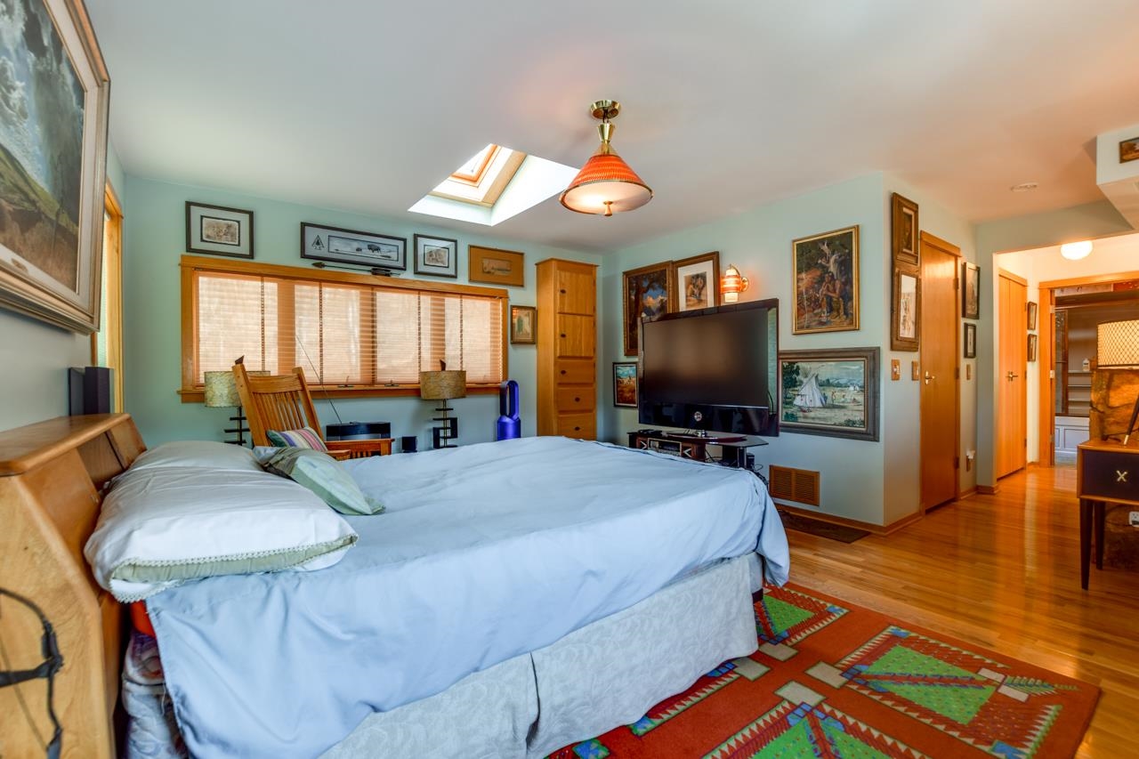 Bedroom with a large bed, skylight, television, and colorful patterned rug.