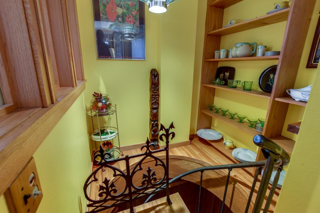 Stair landing with built-in display shelves, hardwood flooring, and an ornate metal railing.