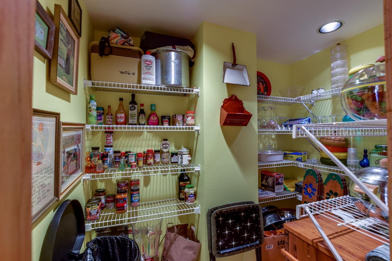 Pantry with white wire shelves packed with groceries, jars, and kitchenware.