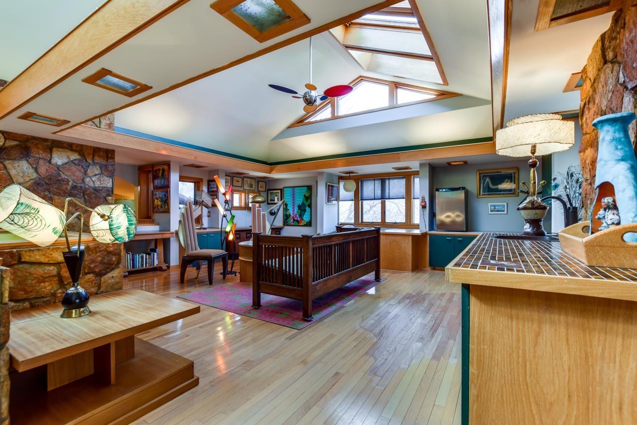 Kitchen with teal cabinetry, a wood peninsula, stone walls, and a vaulted skylight ceiling.