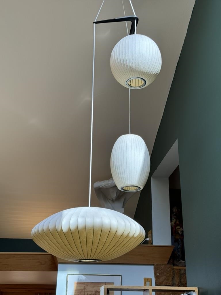 Three white sculptural pendant lights hang at different heights beneath a high ceiling.