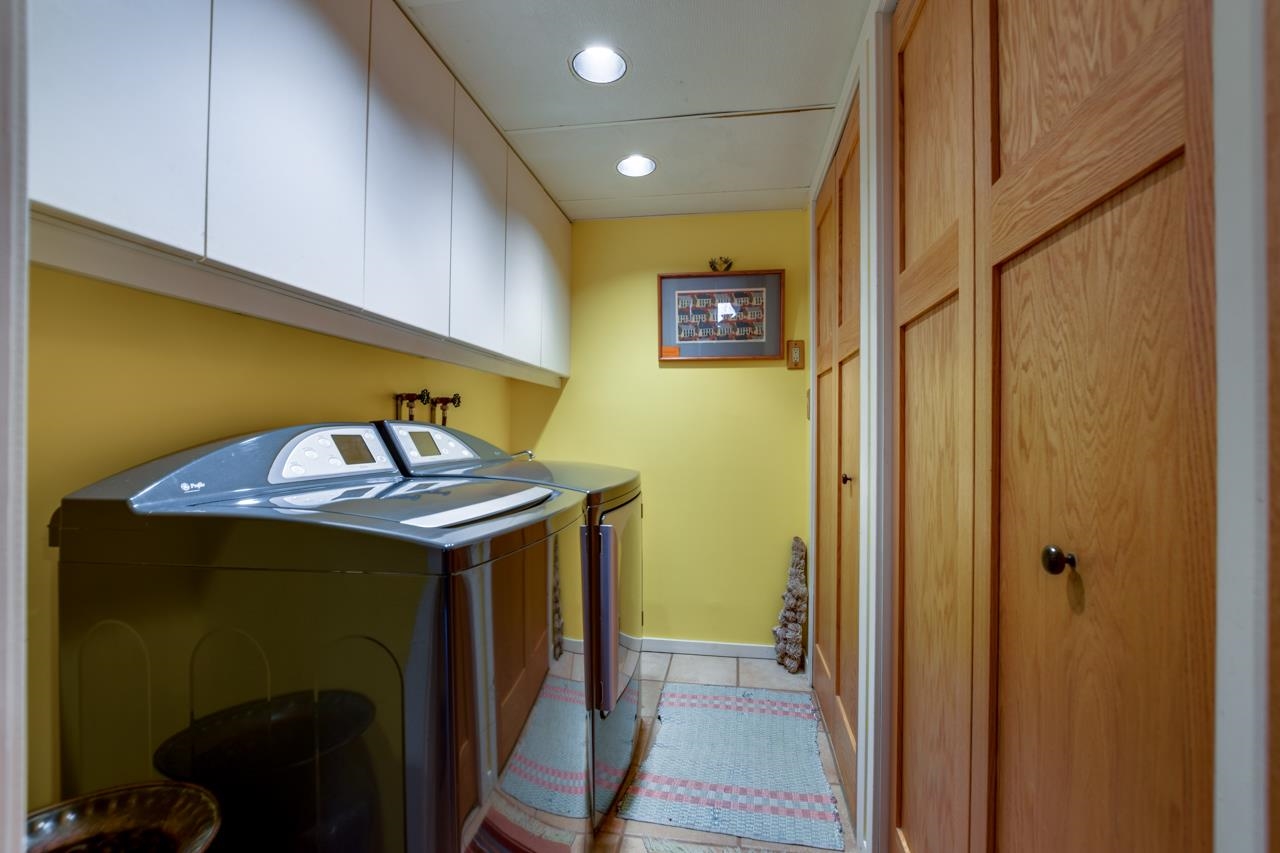 Laundry room with washer and dryer, white cabinets, yellow walls, and wooden paneled doors.