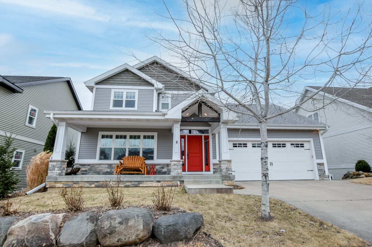 Gray two-story house with a red front door, stone porch, and attached two-car garage.
