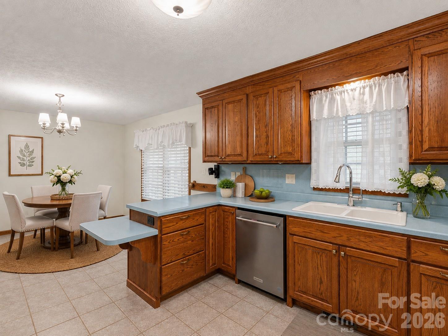 Kitchen with wood cabinets, pale blue counters, a white double sink, and an adjoining round-table dining nook.