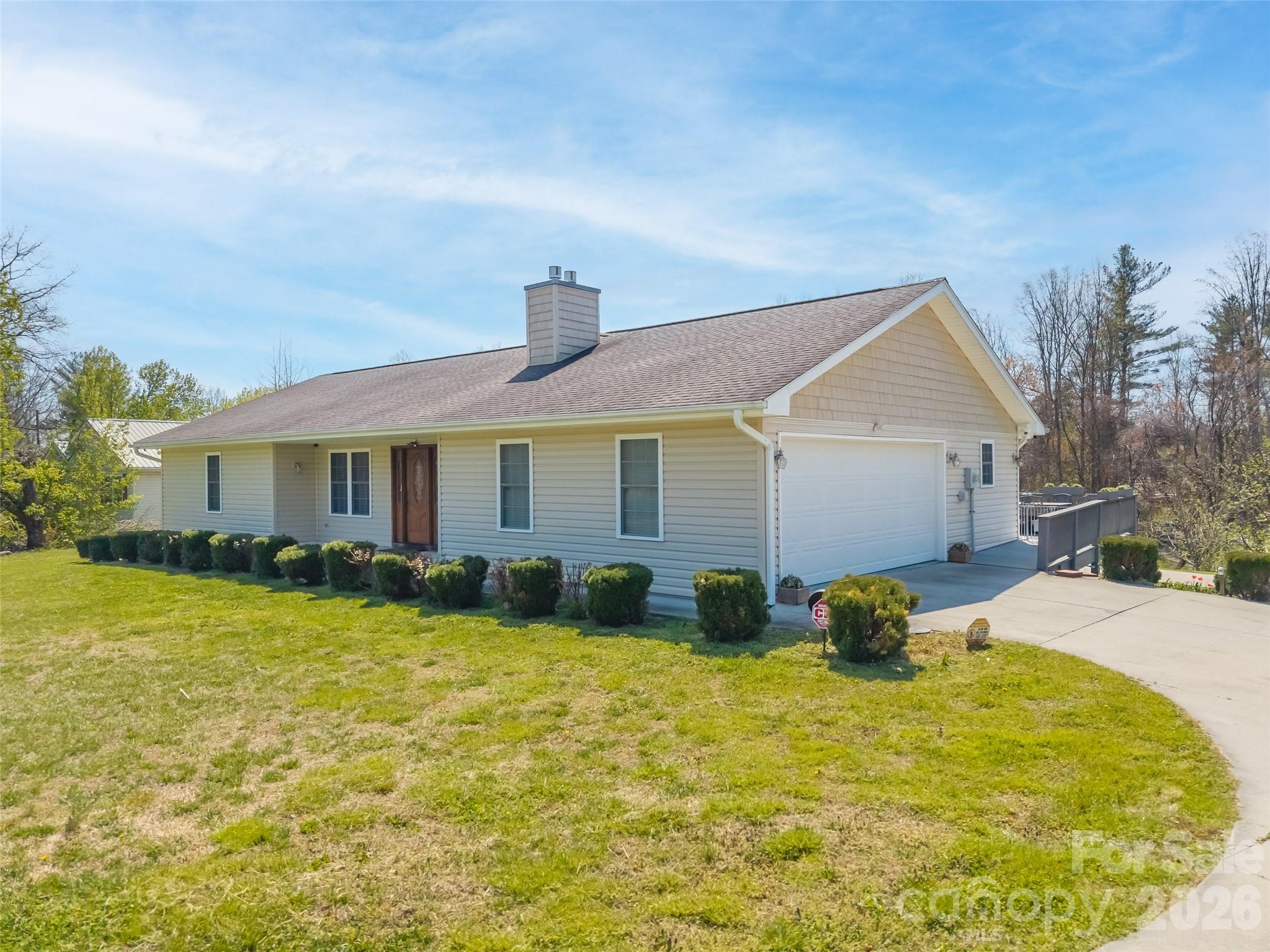 Single-story home with an attached two-car garage, front shrubs, and a broad driveway.