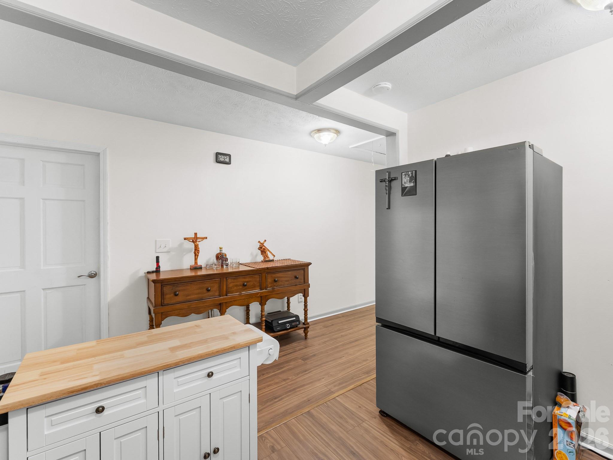 Kitchen with a butcher-block island, stainless steel refrigerator, and warm wood flooring.