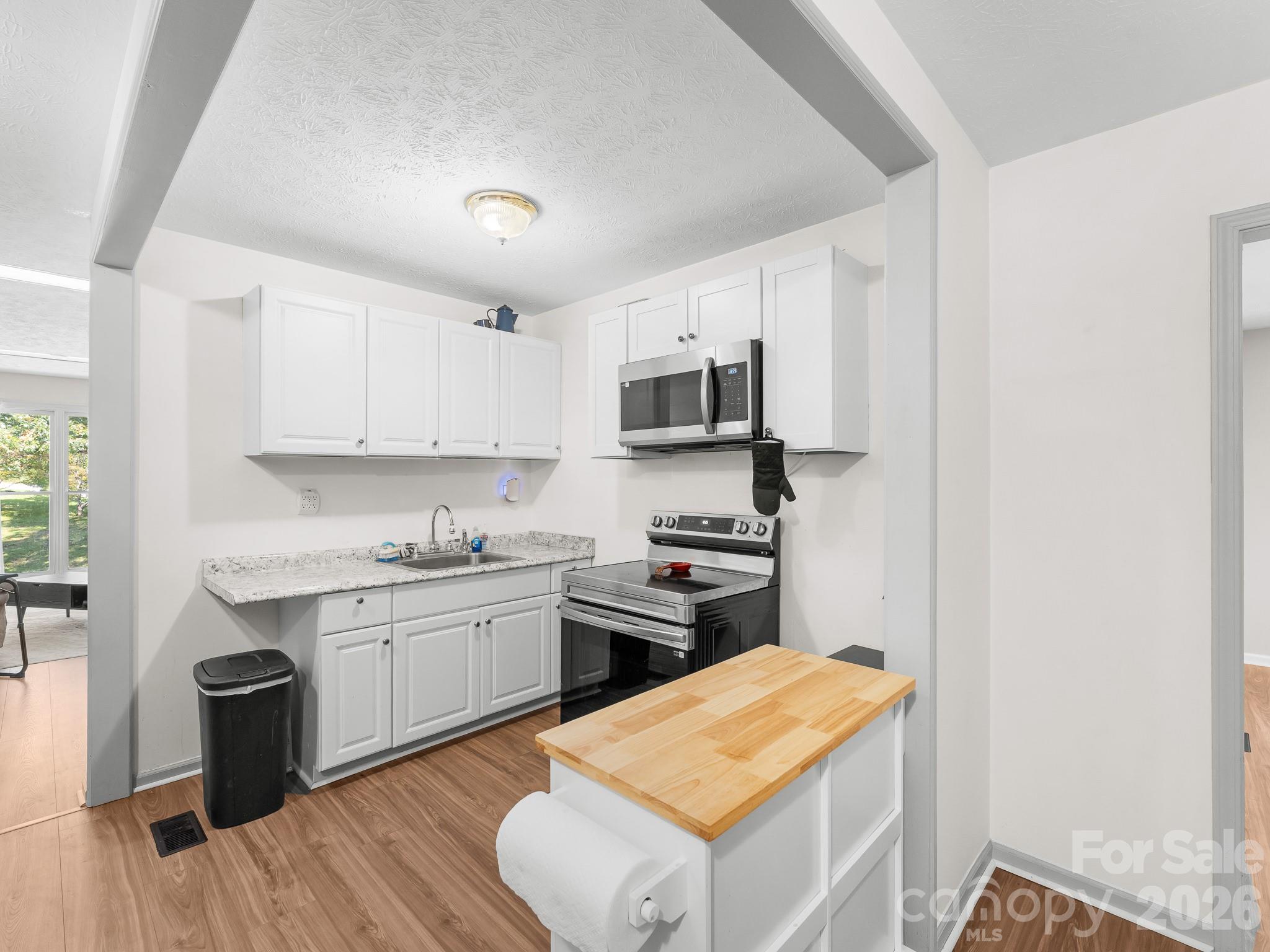 Kitchen with white cabinets, stainless steel appliances, and a butcher-block-topped island.