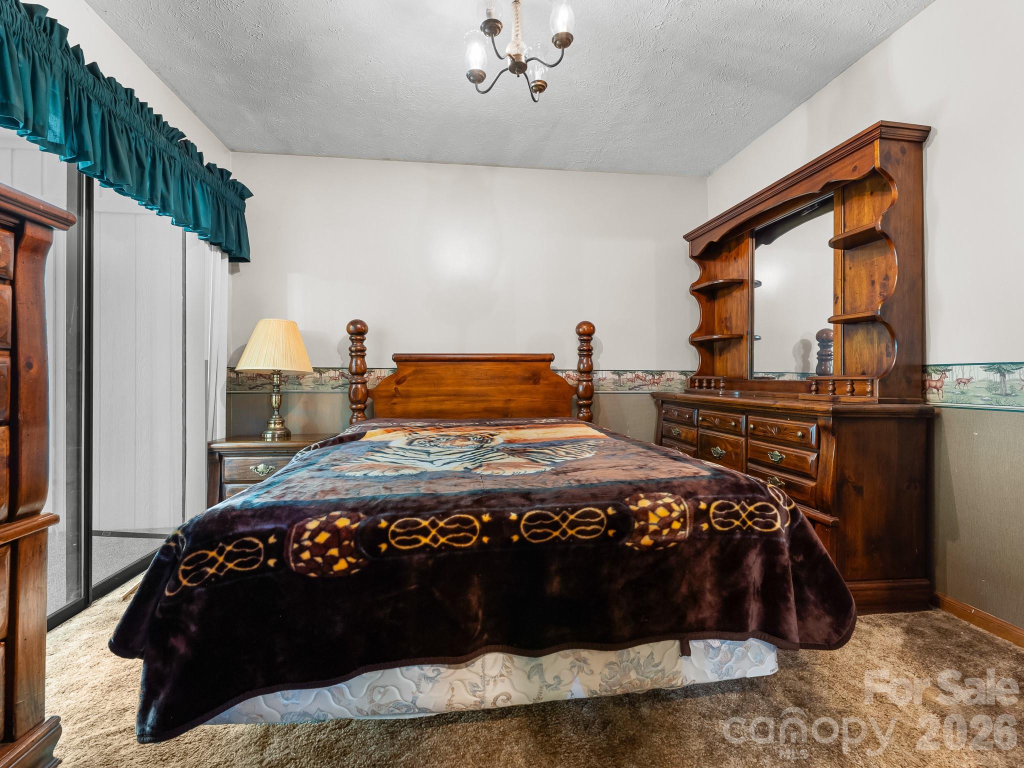 Bedroom with a wooden four-poster bed, patterned blanket, and matching dresser and mirror.