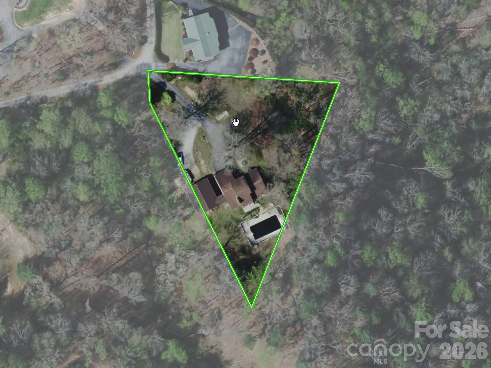 Aerial view of wooded property outlined in green, with a house and swimming pool.