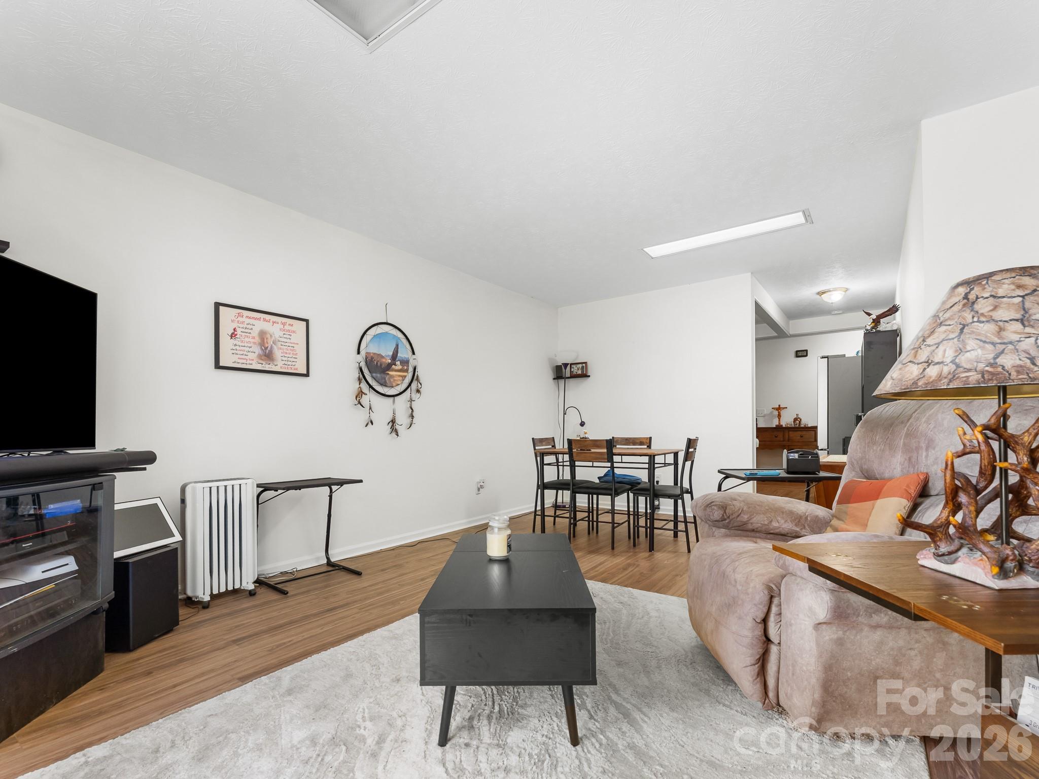 Living room with a dark coffee table, pale rug, recliner, and dining area beyond.