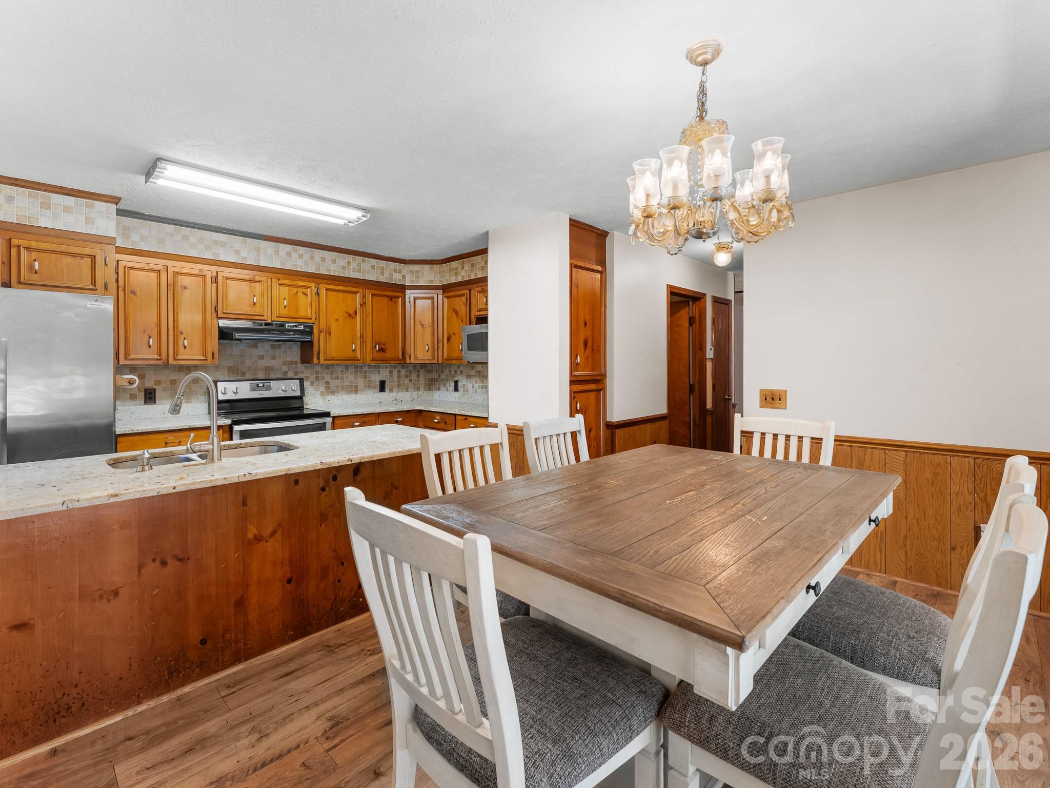 Kitchen and dining area with honey-colored wood cabinetry, a stone-topped island, and a large wood table.