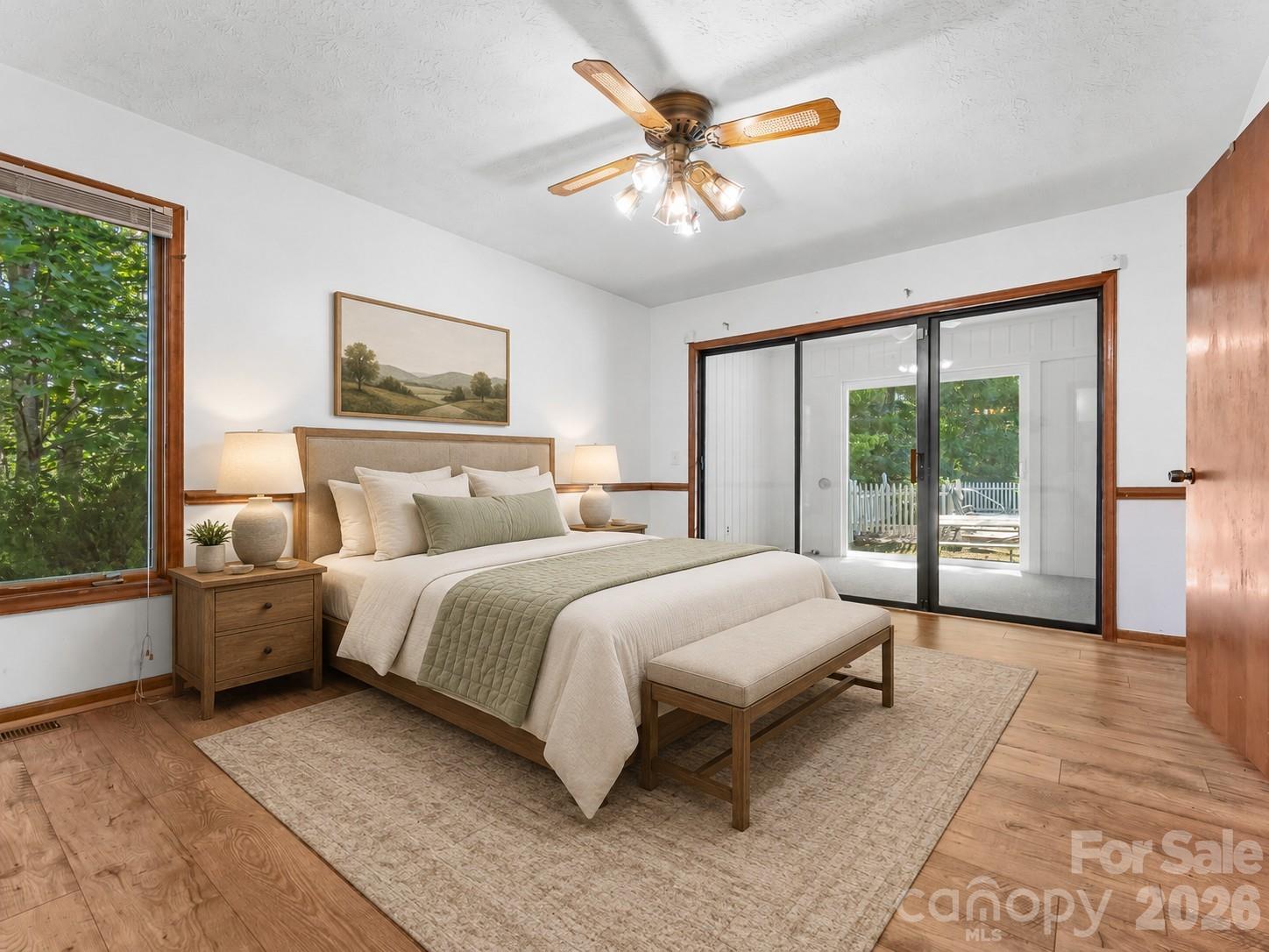 Furnished bedroom with a king bed, wood floors, and sliding glass doors to a patio.