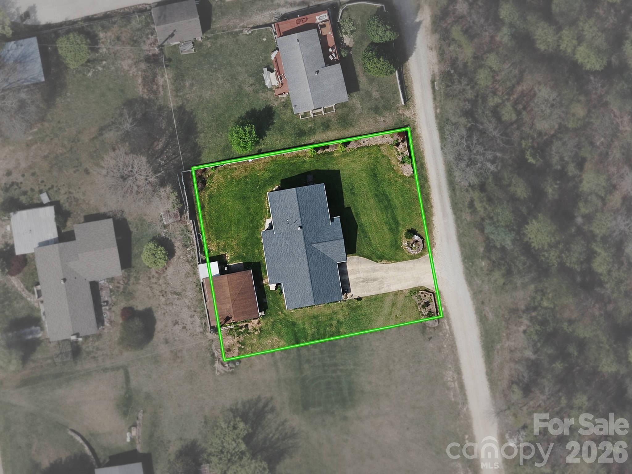 Aerial view of a house and green-outlined lot, with a driveway leading to the road.