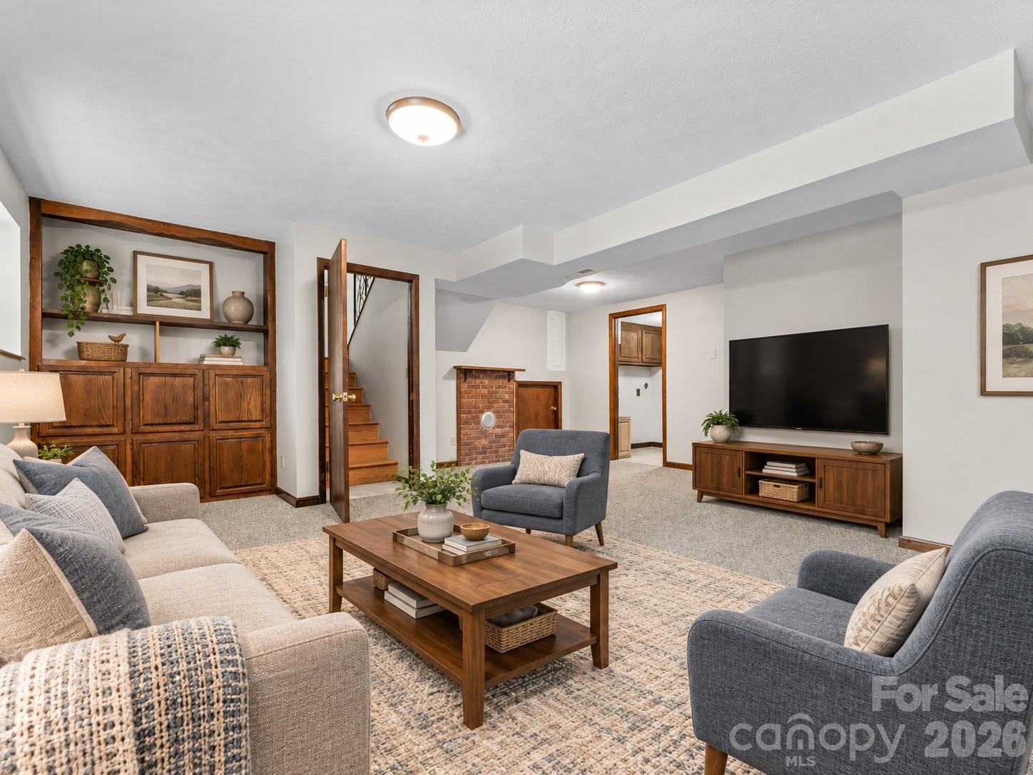 Staged living room with a brick fireplace, built-in wooden cabinetry, and a television.