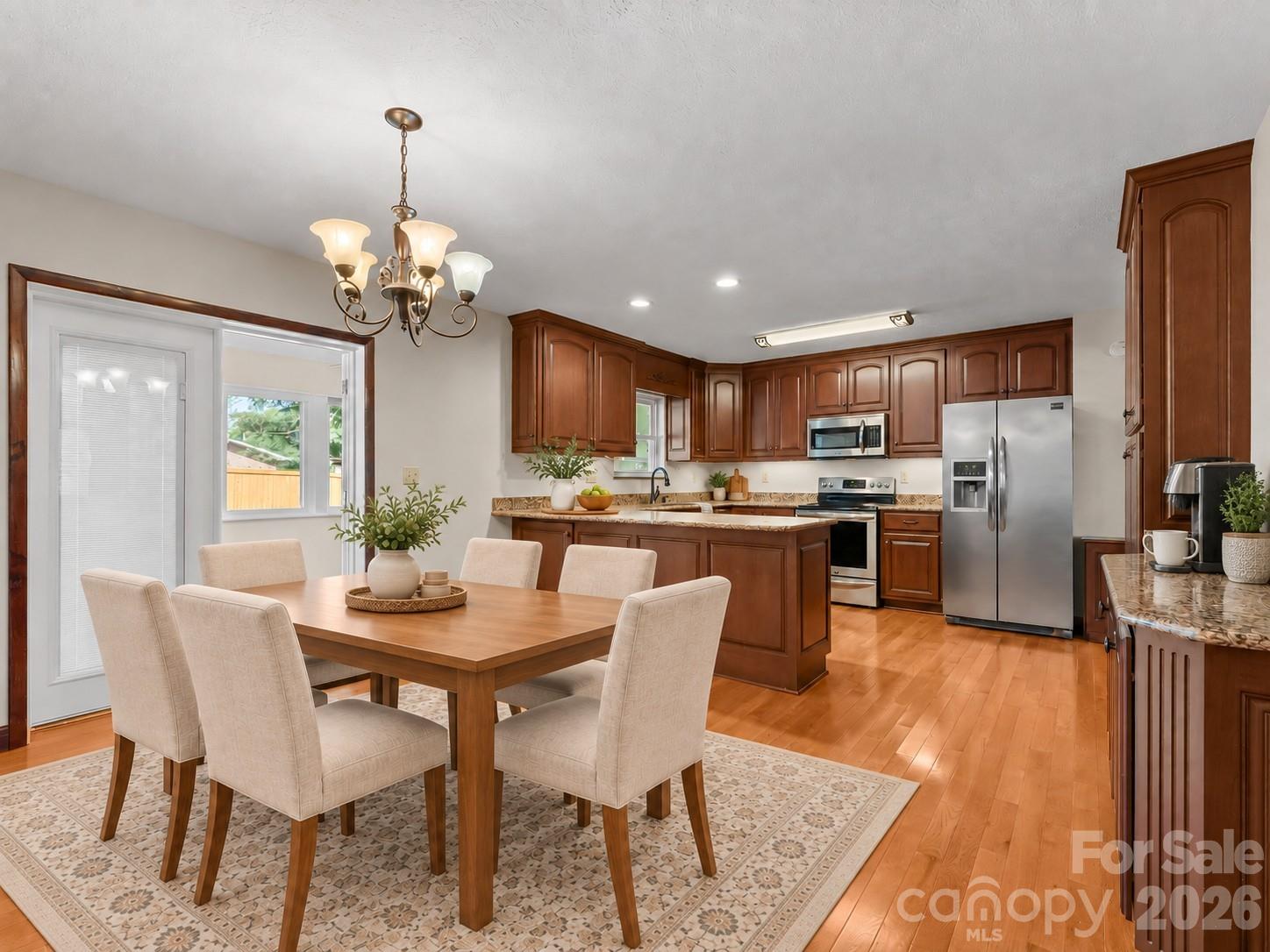 Kitchen and dining area with dark wood cabinetry, stainless steel appliances, and a central island.