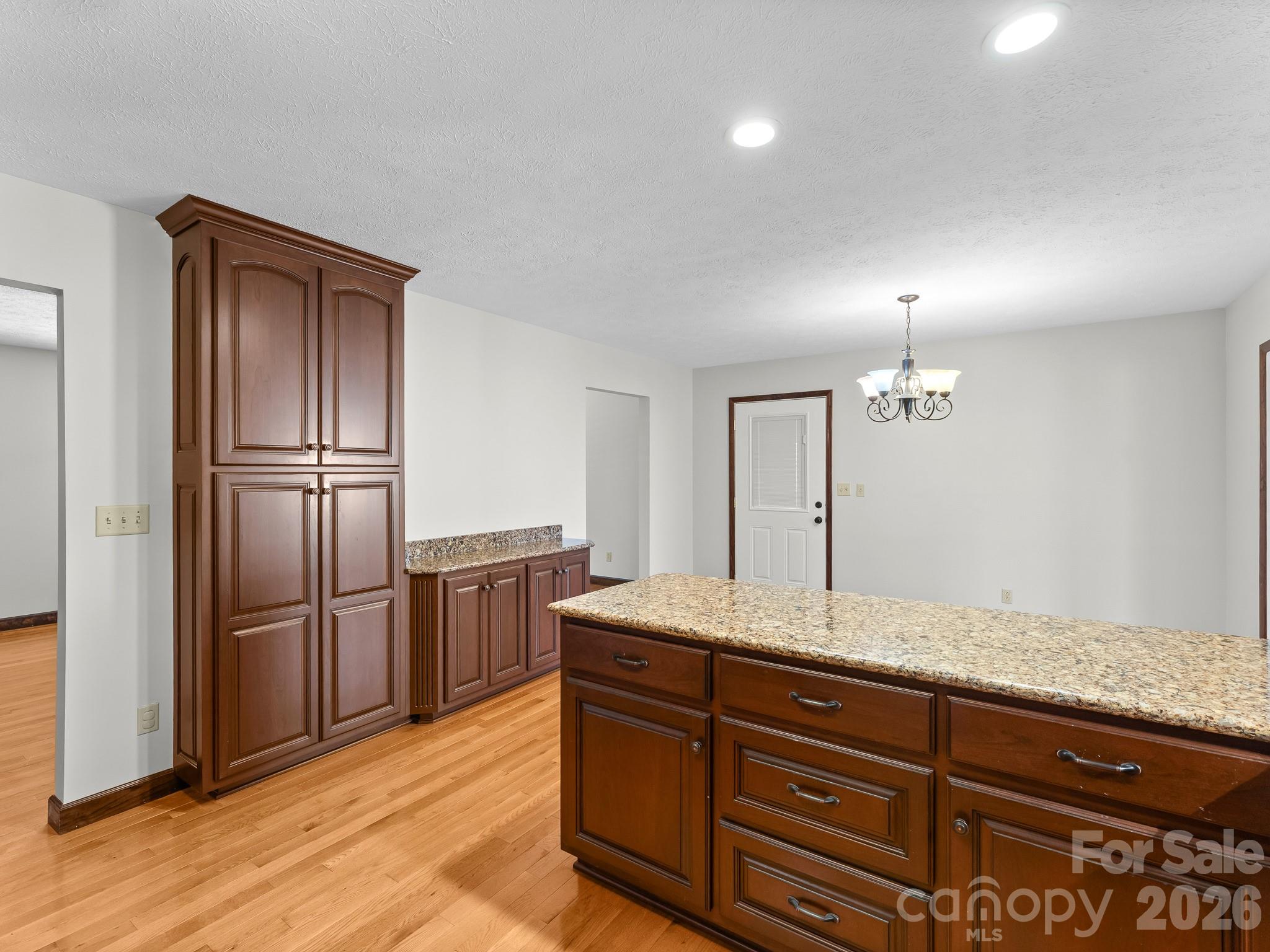 Kitchen with dark wood cabinetry, a granite-topped island, and hardwood floors.