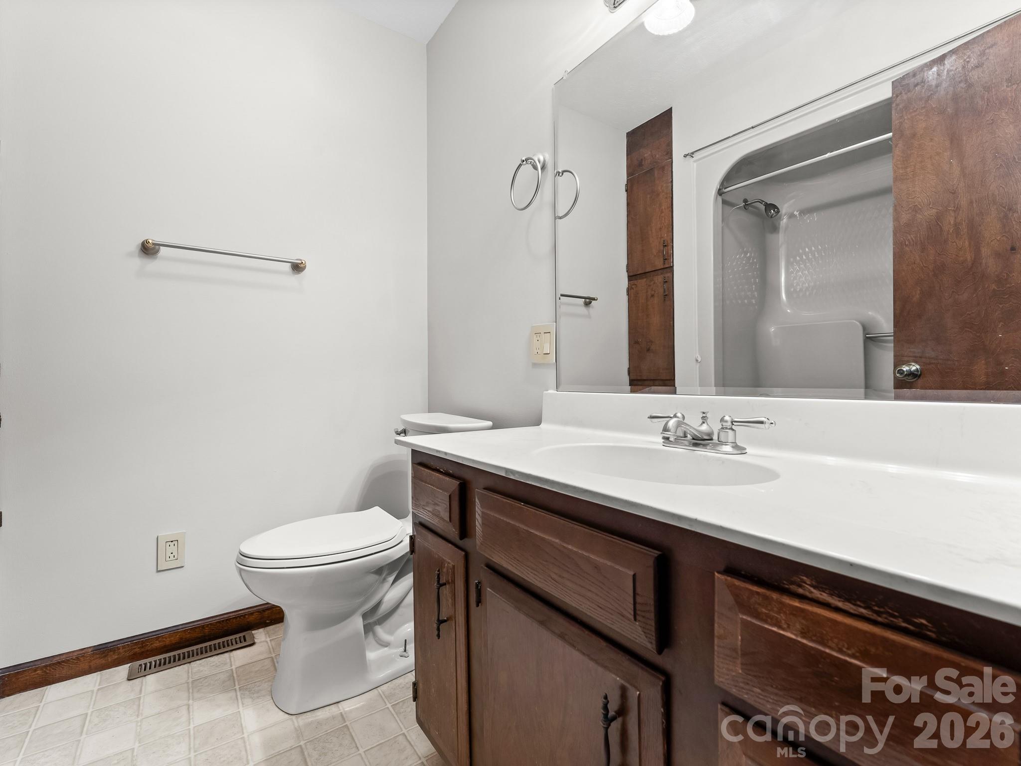 Bathroom with a dark wood vanity, white sink, toilet, and tub-and-shower enclosure.