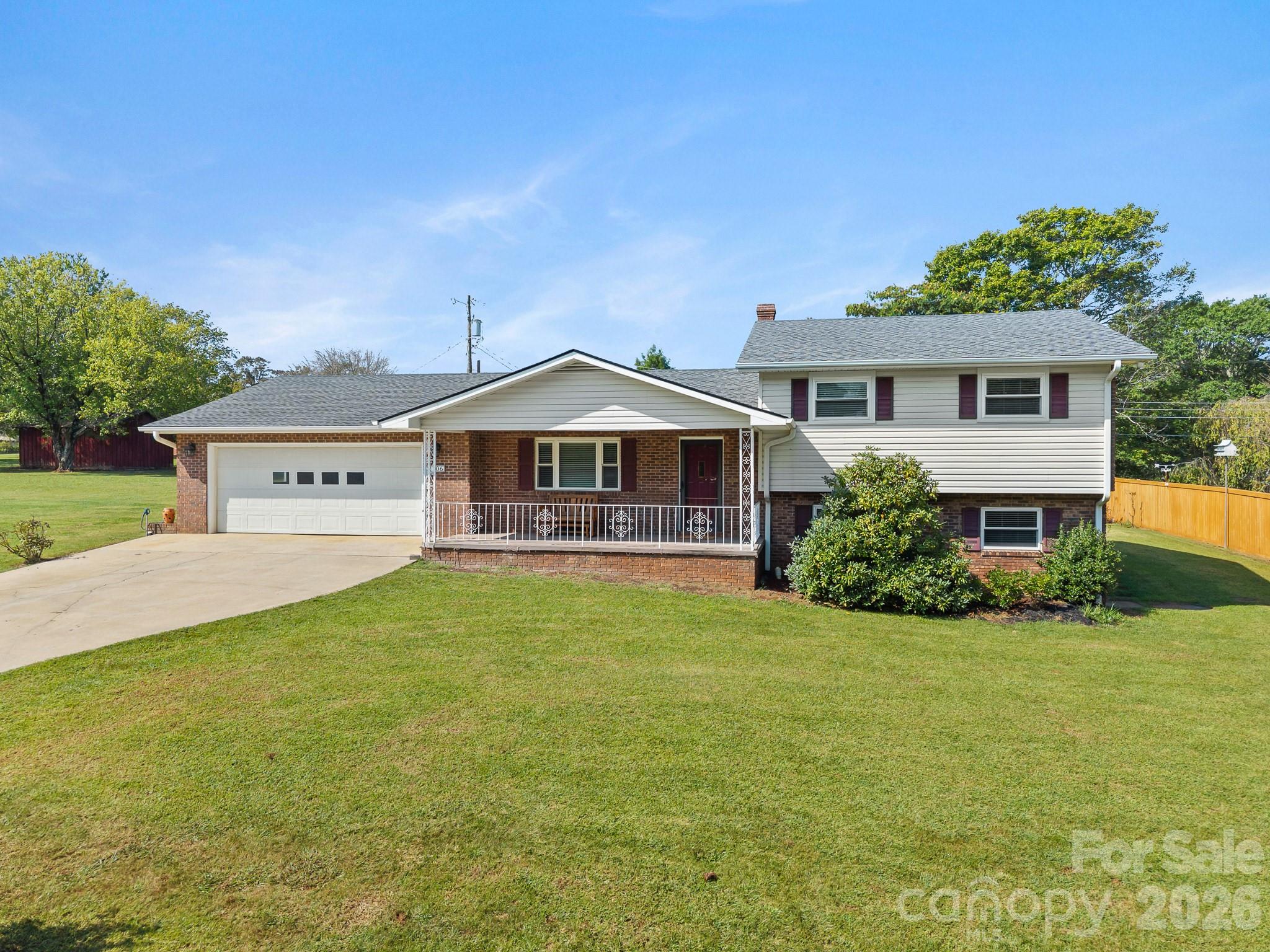 Split-level home with brick and light siding, a covered porch, attached garage, and broad front lawn.